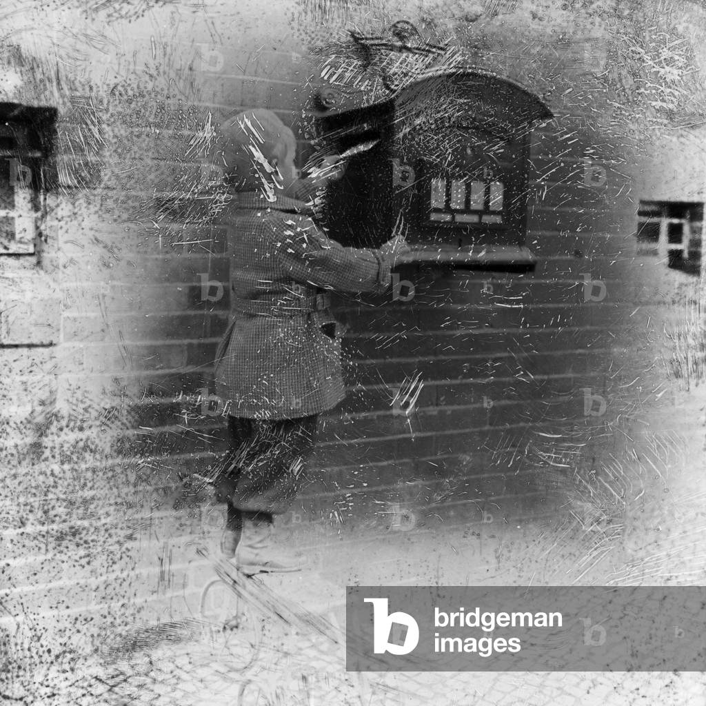 A little boy bringing a letter to the letter box, Germany 1920s (b/w photo)