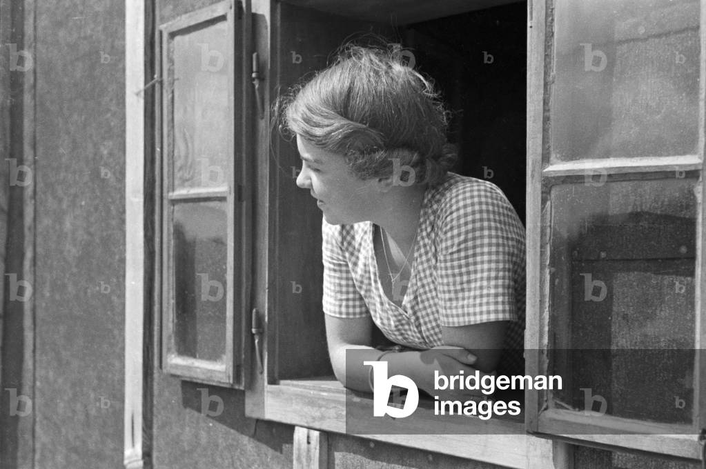 A young woman looking out of the window, Germany 1930s (b/w photo)