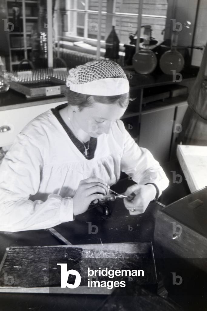 A lab assistant is filling up medication in the laboratory of the Behringwerke, Marburg, Germany 1930s (b/w photo)