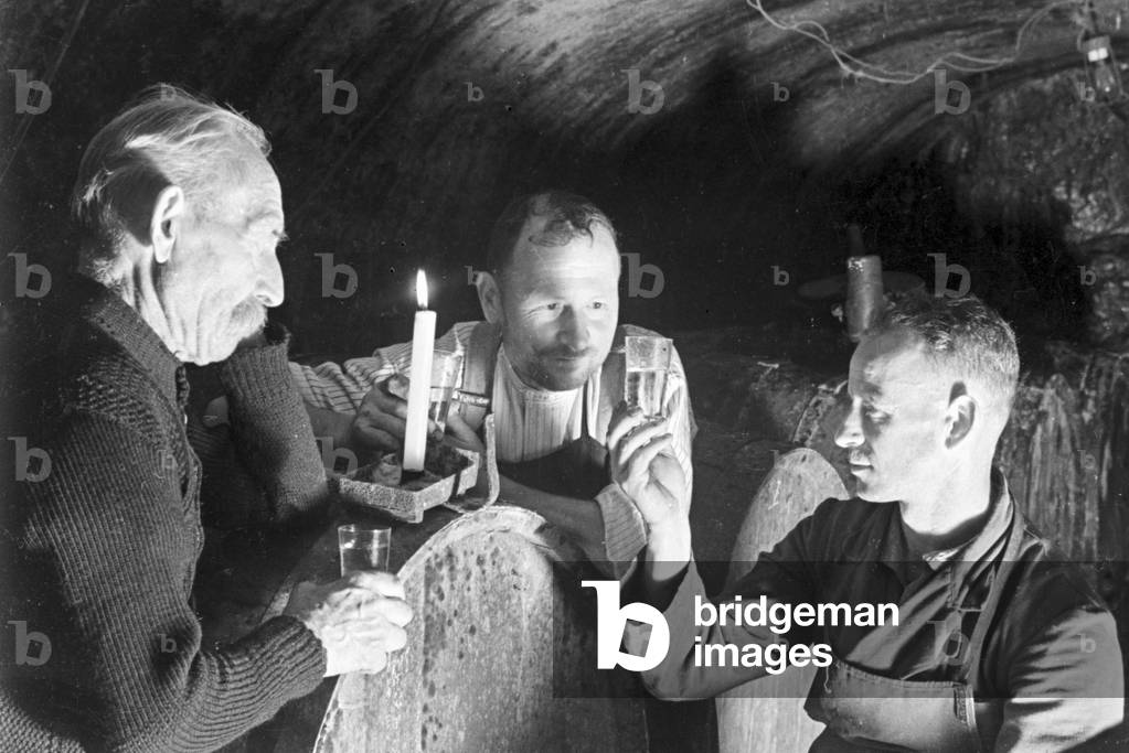 Three winegrowers checking the new vintage at the wine cellar, Germany 1930s (b/w photo)