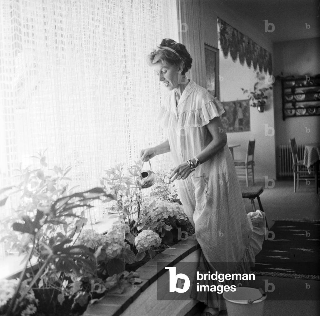 German singer and actress Lale Andersen watering the flowers at her house, called Sonnenhof, on the East Frisian island Langeoog, mid 1957