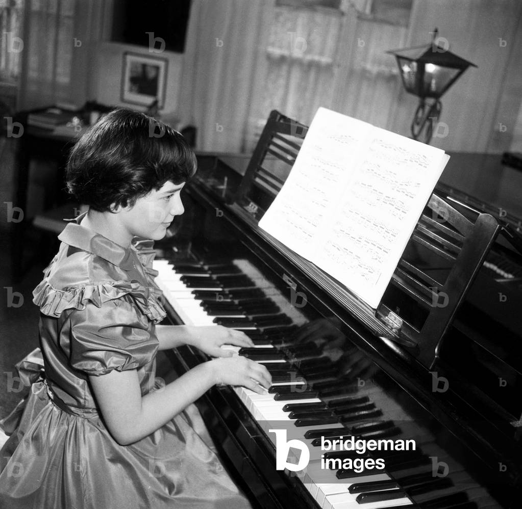 A little girl playing a grand piano