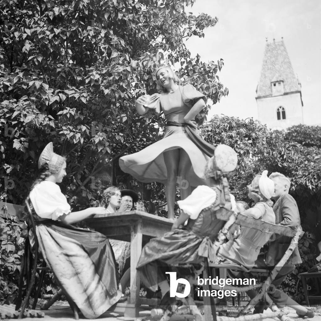 A young woman tasting the wine of the Wachau area in Austria and dancing on the table, Germany 1930s (b/w photo)