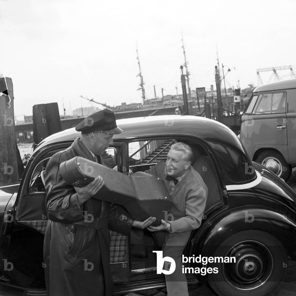A taxi driver helping lutenist Richard Germer to enter the taxi at Hamburg, Germany 1950s