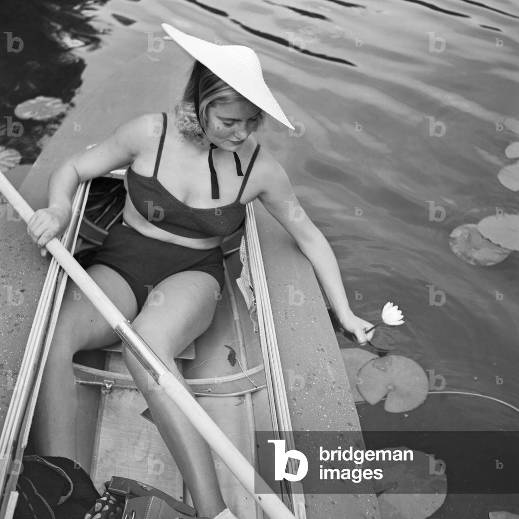 A young woman with her folding boat in the reed of a lake in the Wachau area, Germany 1930s (b/w photo)