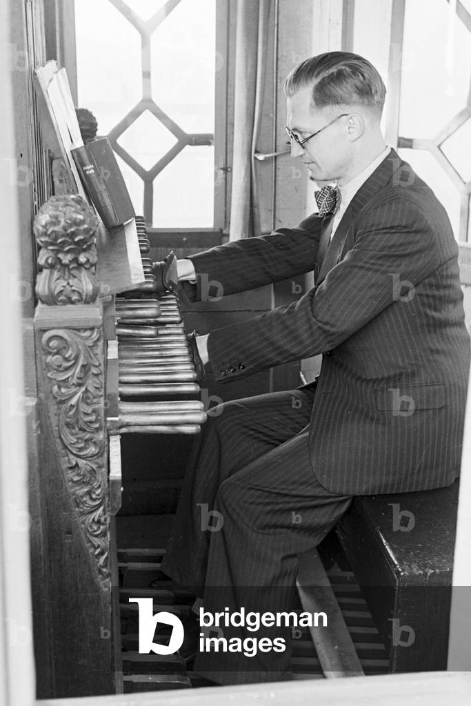 A carillonneur at the carillon keyboard in the Parochialkirche in Berlin, Germany 1930s (b/w photo)