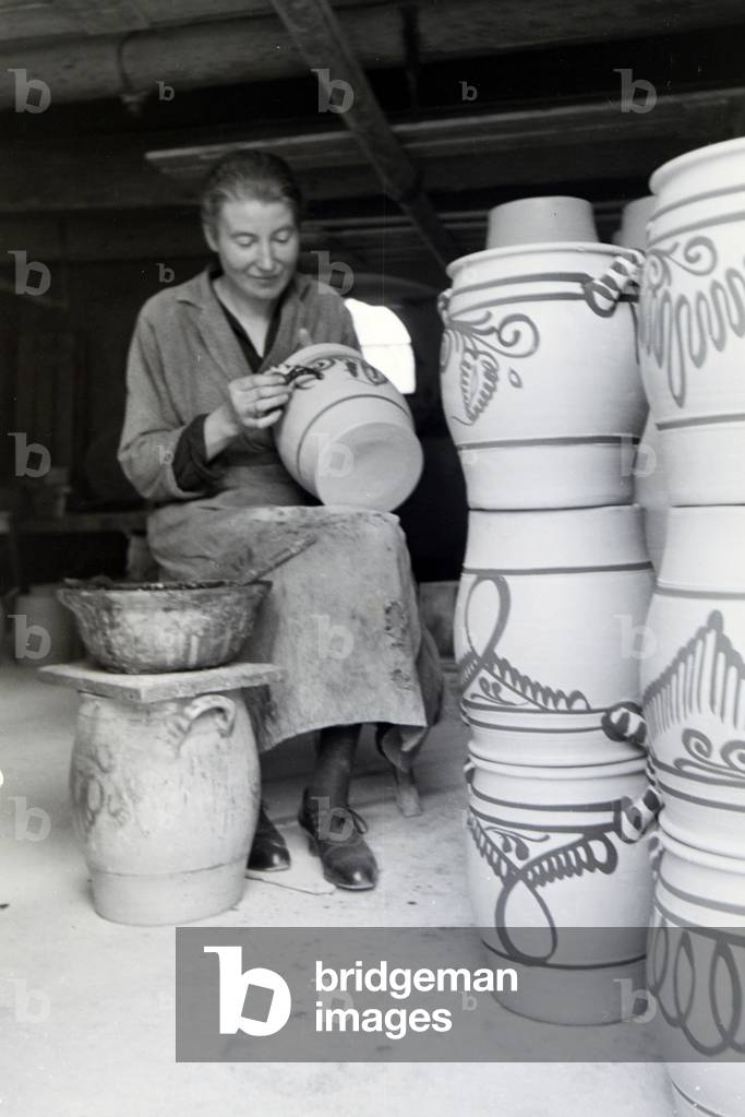 A master potter painting stoneware jars in the characteristic blue colour of the Westerwälder Stoneware, Germany 1930s (b/w photo)