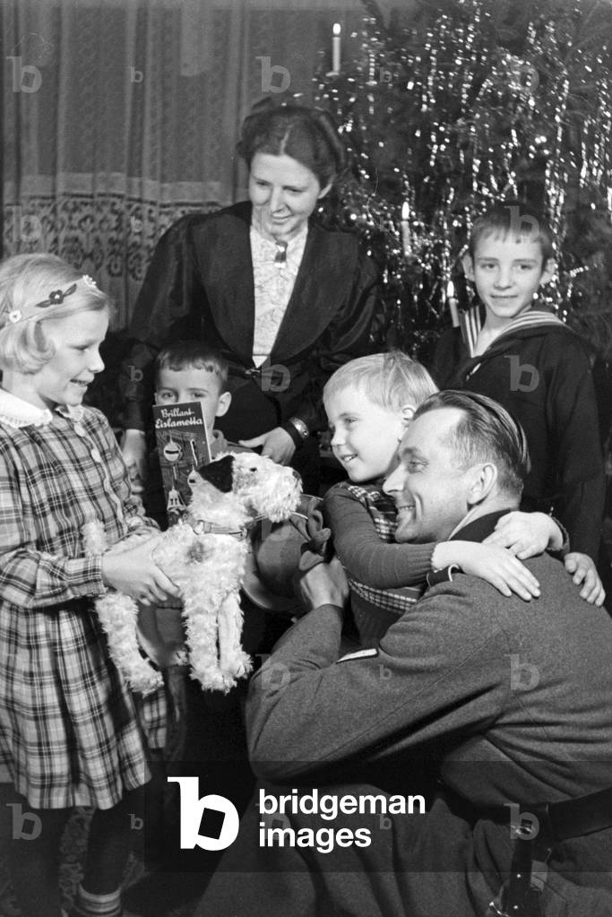 A soldier is with his family in his christmas holidays, Germany 1930s (b/w photo)