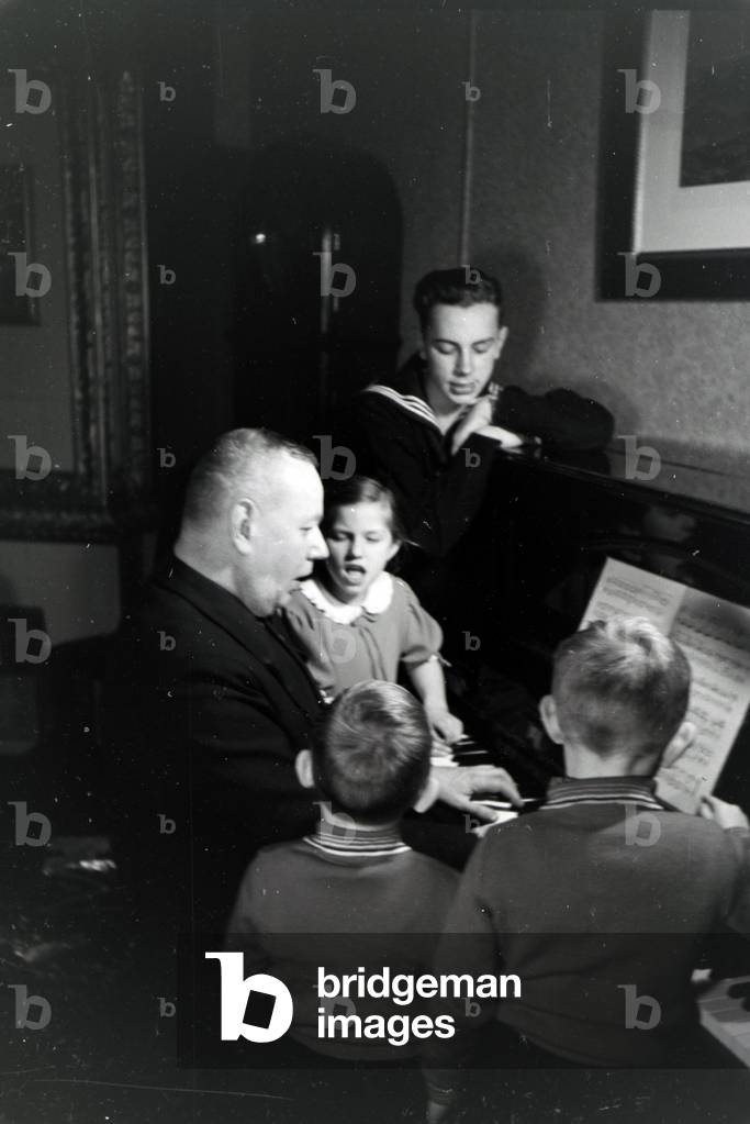 Members of an extended family playing the piano, Germany 1930s (b/w photo)