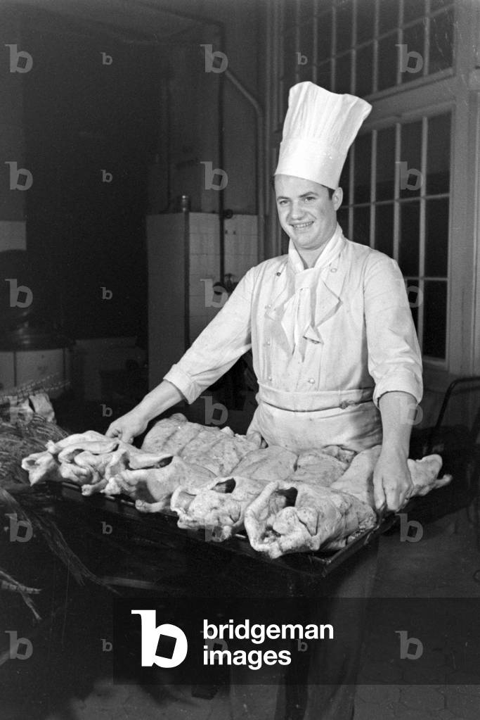 A chef with fresh poultry at the kitchen of a restaurant, Germany 1930s (b/w photo)