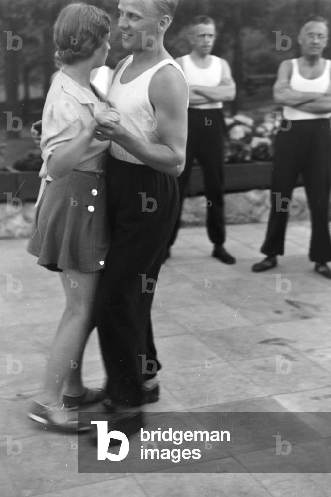 People singing and dancing in front of forest huts at the sports club at Belzig in Brandenburg, Germany 1930s (b/w photo)