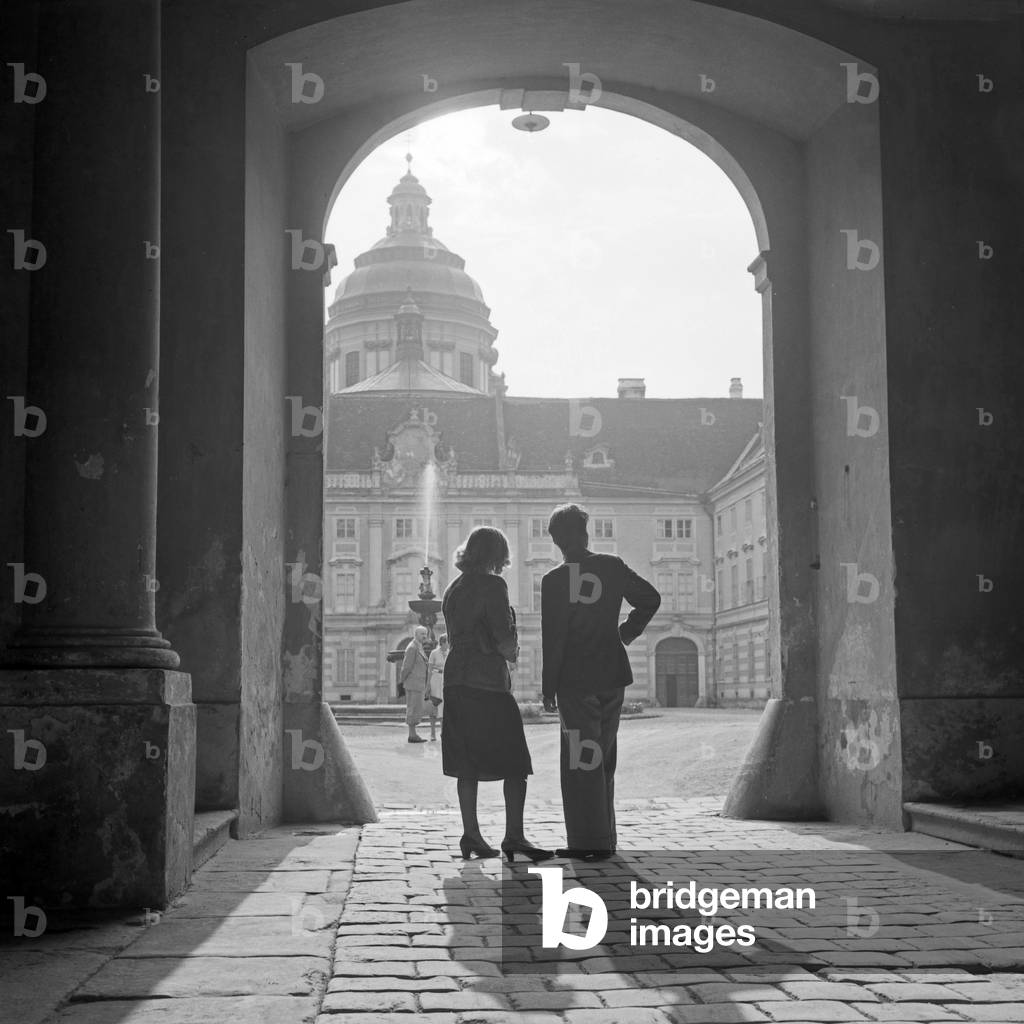 A man and a woman standing in the archway at the entrance to Melk Abbey, Austria 1930s (b/w photo)