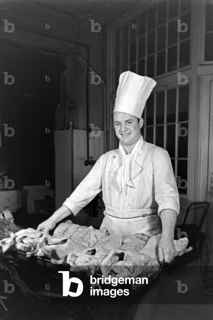A chef with fresh poultry at the kitchen of a restaurant, Germany 1930s (b/w photo)