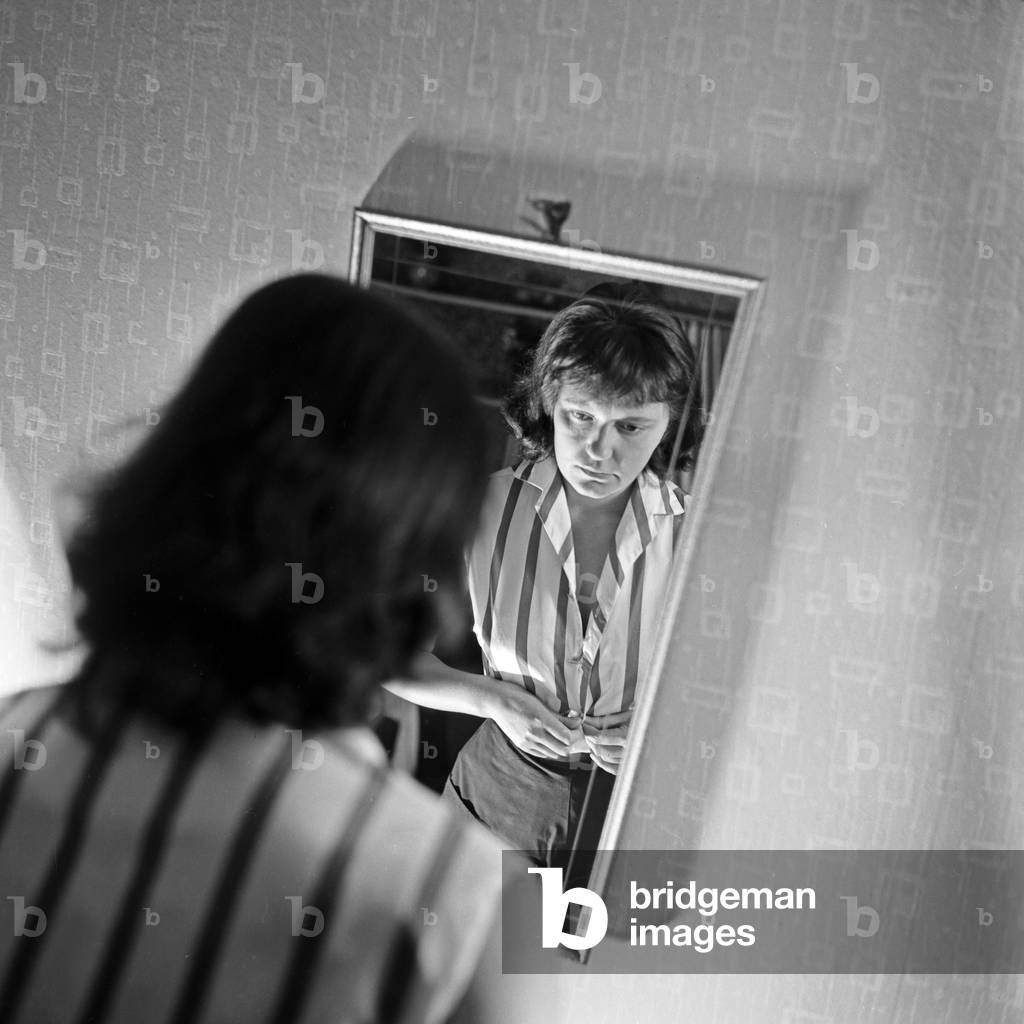 A young woman dressing up in front of her mirror, Germany 1950s