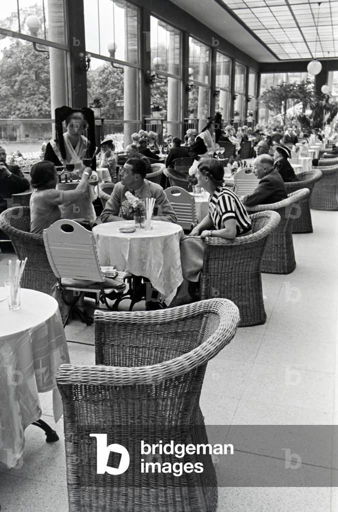 Visitors of the restaurant in the Kurhaus Casino in Baden-Baden are being served by waitresses wearing a traditional Black Forrest costume with the Bollenhut, Germany 1930s (b/w photo)