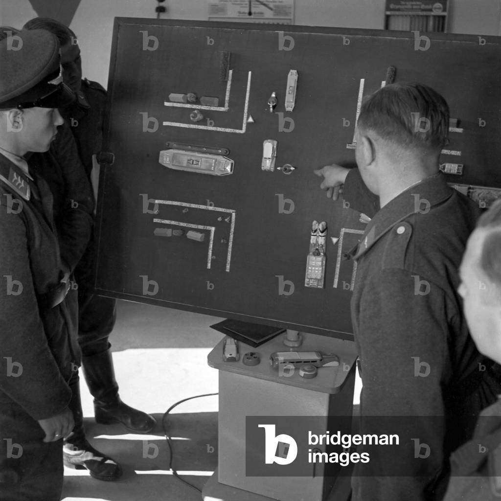 Theoretical lessons at a traffic board belongs also to the driving education of signal soldiers, Germany 1940s (b/w photo)