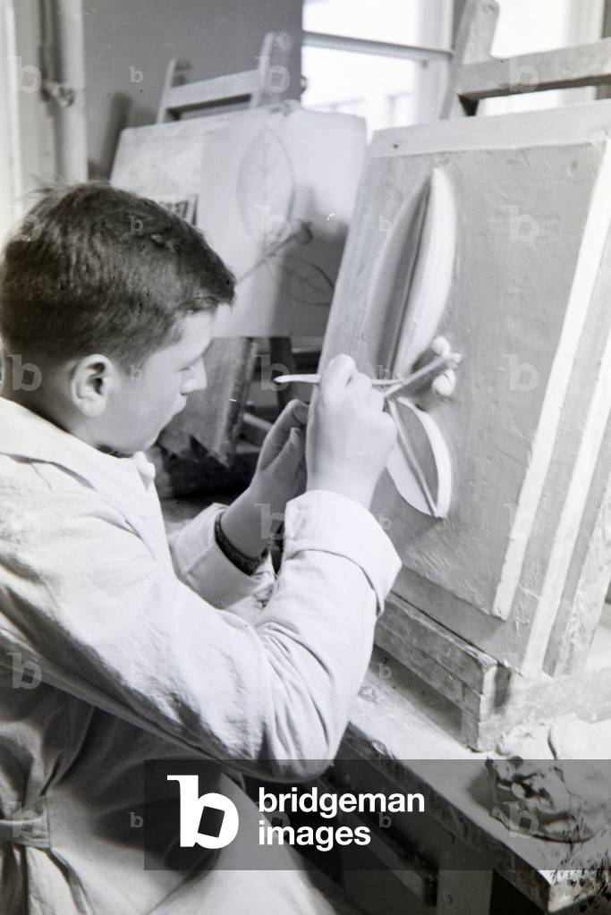 A student of the College for Ceramics working on a relief in the shape of a flower in the working ateliers, Höhr-Grenzhausen, Germany 1930s (b/w photo)