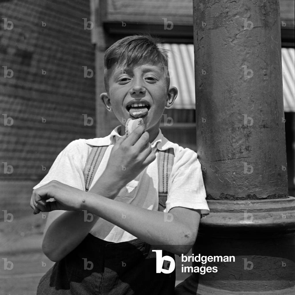 A boy licking his ice cream wafer, Germany 1930s (b/w photo)