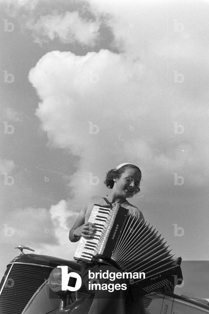 A young woman playing the harmonica, Germany 1930s (b/w photo)