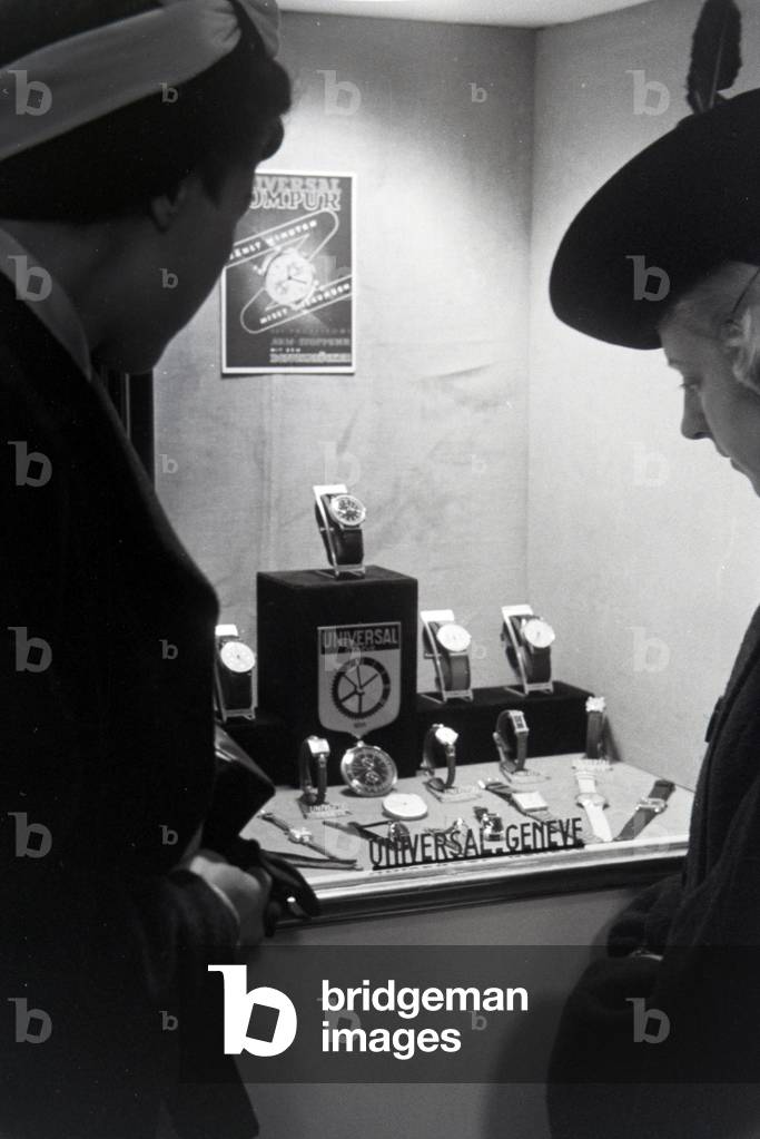 Visitors to a fair in front of a display case with watches made by the Swiss company Universal Genève, on the occasion of the Wiener Modewoche in the house of fashion 