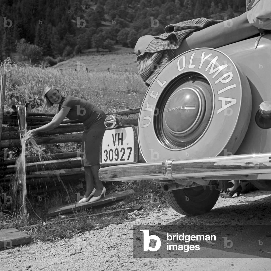 A young woman resting and cooling while a trip with an Opel Olympia, Austria 1930s (b/w photo)