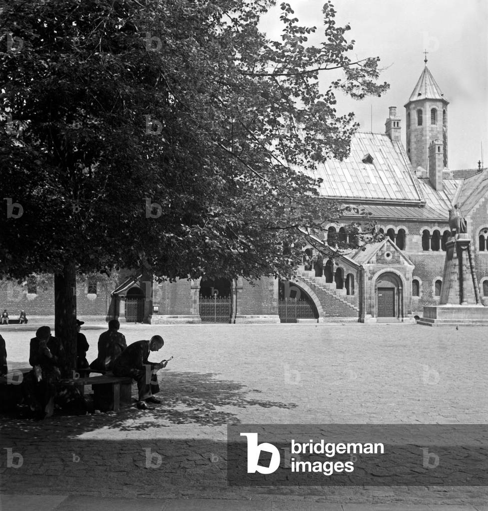 People sitting and relaxing in the shadow of a tree on Burgplatz square at Braunschweig, Germany 1930s (b/w photo)