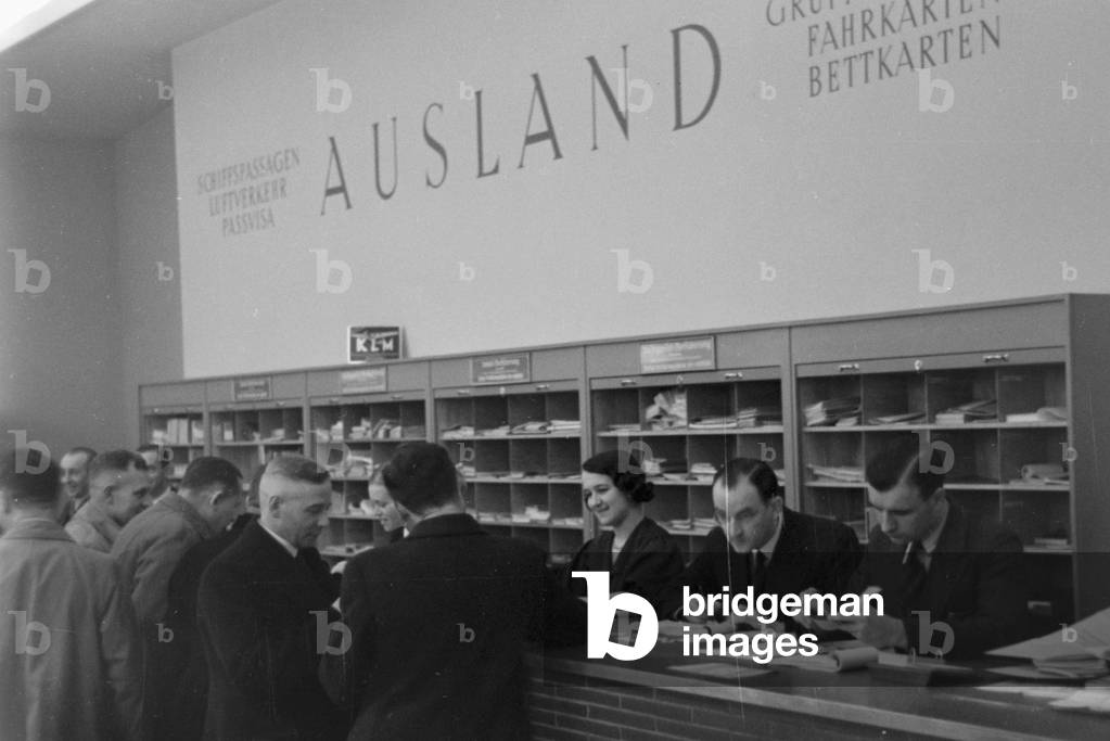 Travellers and staff members at a huge office of a travel agency in Berlin, Germany 1930s (b/w photo)