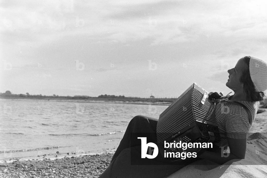 A young woman playing the harmonica, Germany 1930s (b/w photo)