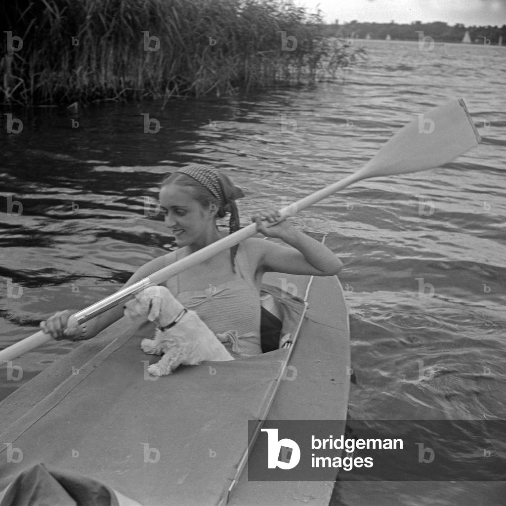 Advertising für a Klepper foldboat: a young woman with a puppy paddling on a lake, Germany 1930s (b/w photo)