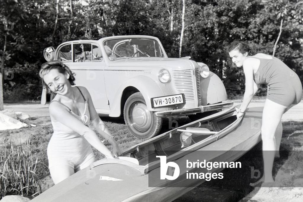 Two young women pulling a boat, Klepper T6 from the coast into the lake, Germany 1930s (b/w photo)