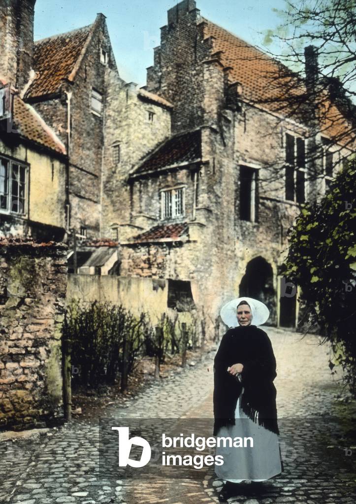 Netherlands, province of Zeeland. Woman in front of the Kuipers portal in the city of Middelburg. Image date: circa 1920. Carl Simon Archive