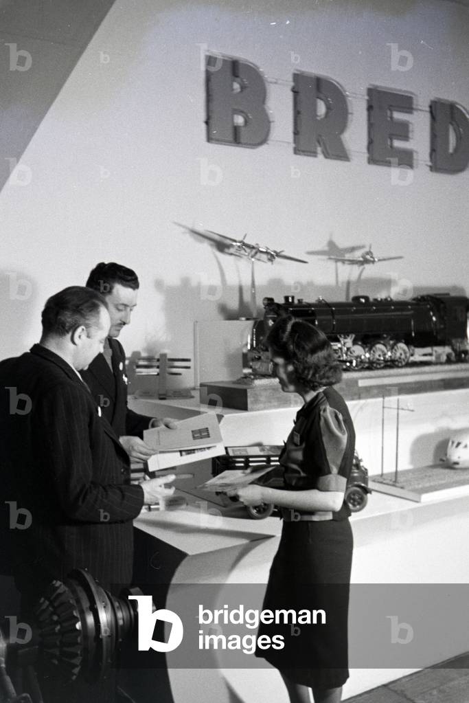 Visitors in front of a stand with models of the italian mechanical engineering corporation Breda on the Leipziger Frühjahrsmesse, Germany 1941 (b/w photo)