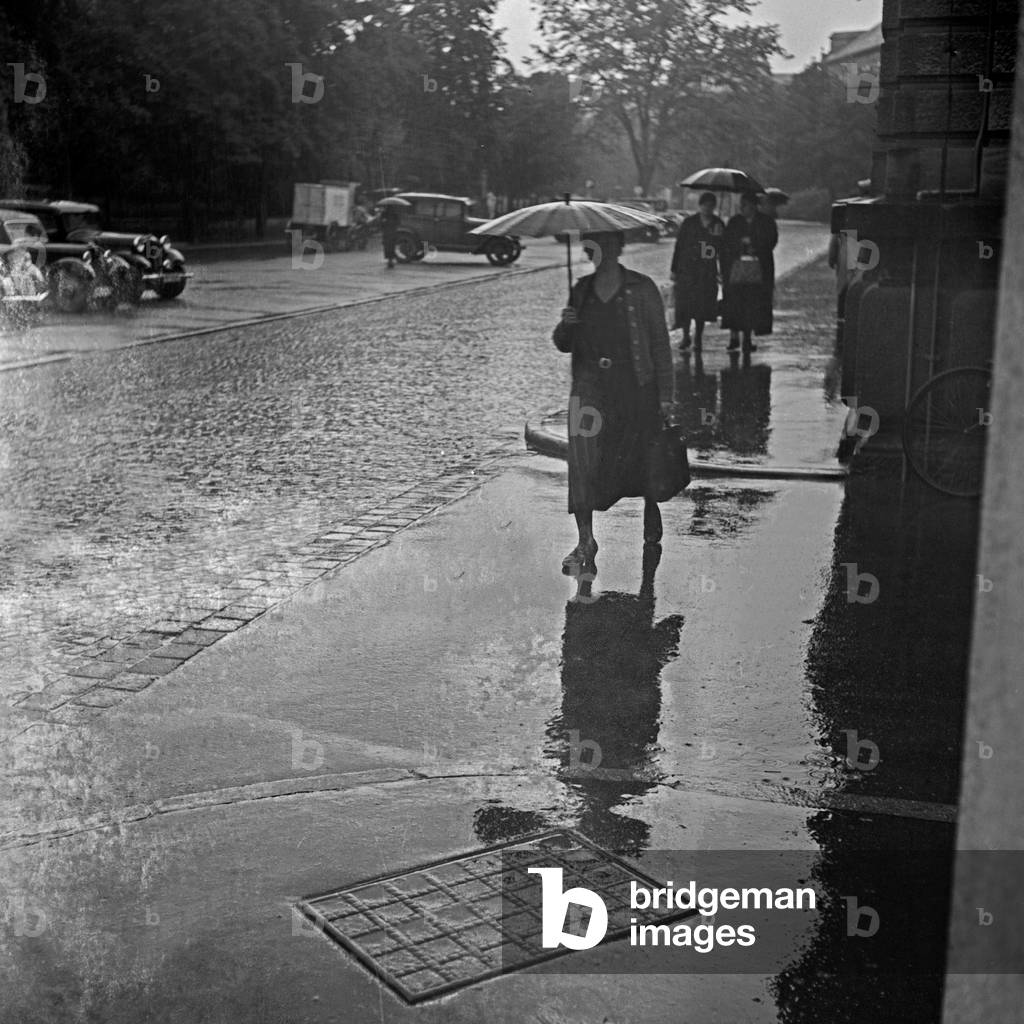 A woman in the rain under an umbrella, Germany 1930s (b/w photo)