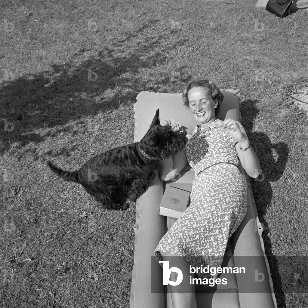 A young woman with her dog on a lawn, Germany 1930s (b/w photo)