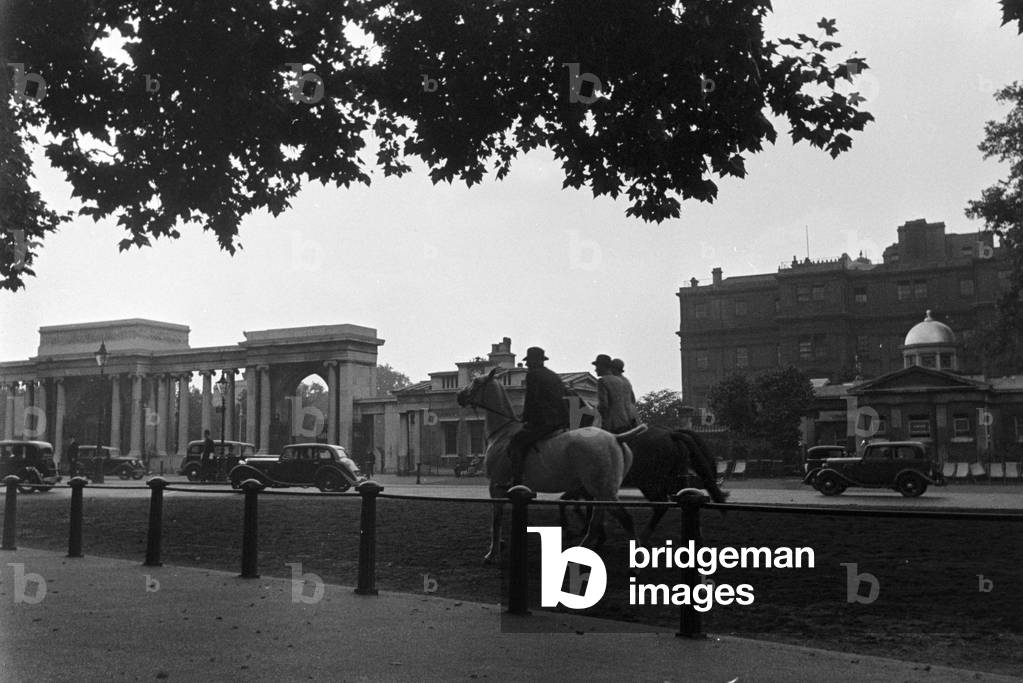Passers by relaxing while watching the traffic at a city centre, Germany 1930s (b/w photo)