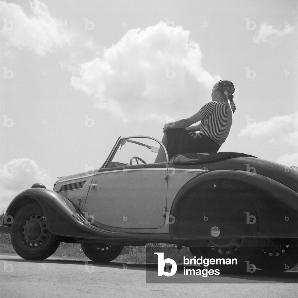 A young woman having a break in her Ford model Eifel, Germany 1930s (b/w photo)