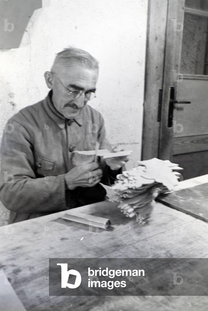 An employee of the Heller Kunst workshops in the Eifel grinding the edges of the sawn out wooden figures, Germany 1930s (b/w photo)