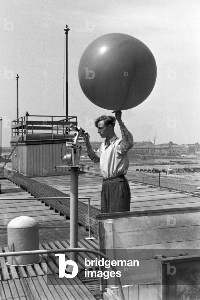Staff member of a meteorological office calibrating analyser and a registering balloon, Germany 1930s (b/w photo)