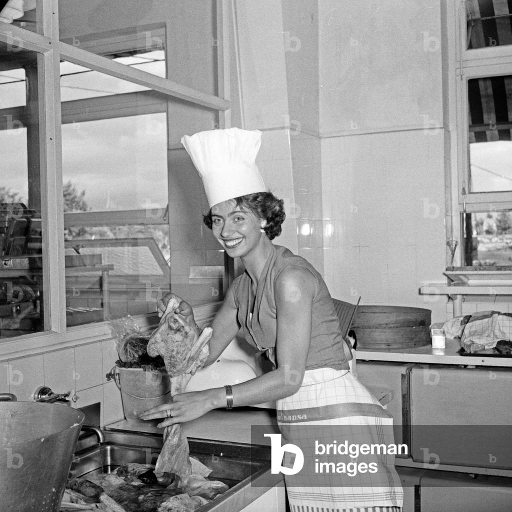 German schlager singer Margot Eskens preparing fried chicken at the kitchen of German Lufthansa airline at Hamburg airport, Germany 1950s