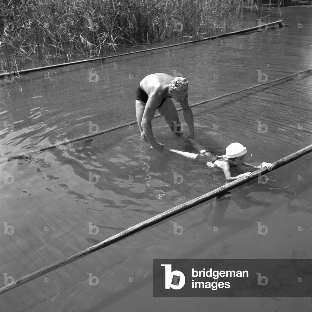 A father teaches his son how to swim, Germany 1930s (b/w photo)