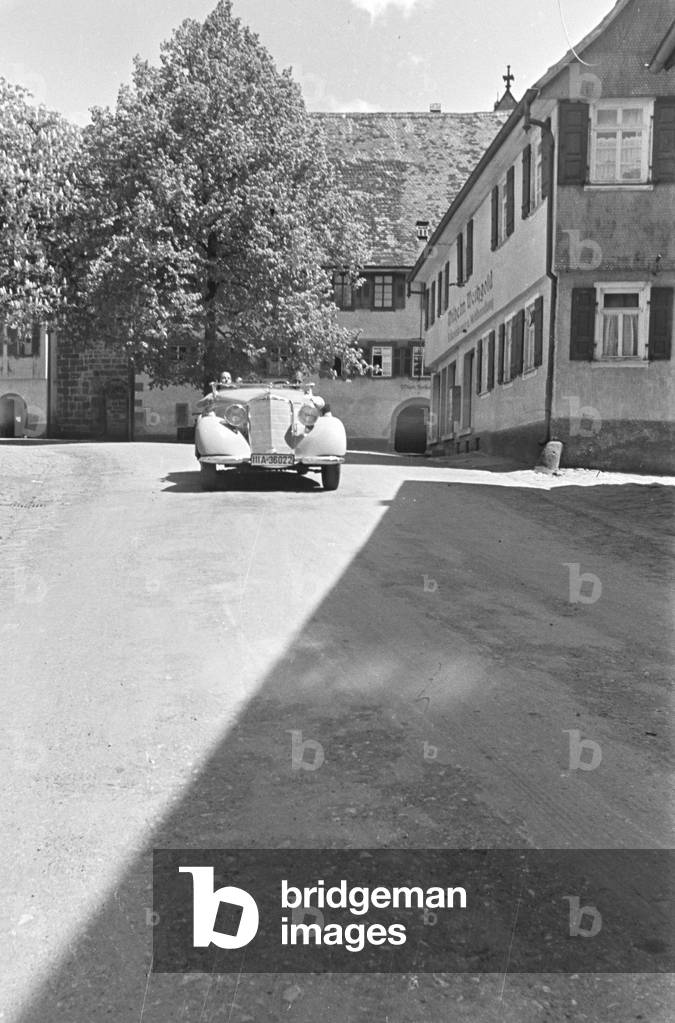 Travellers driving through the town Alpirsbach in the Black Forest, Germany 1930s (b/w photo)
