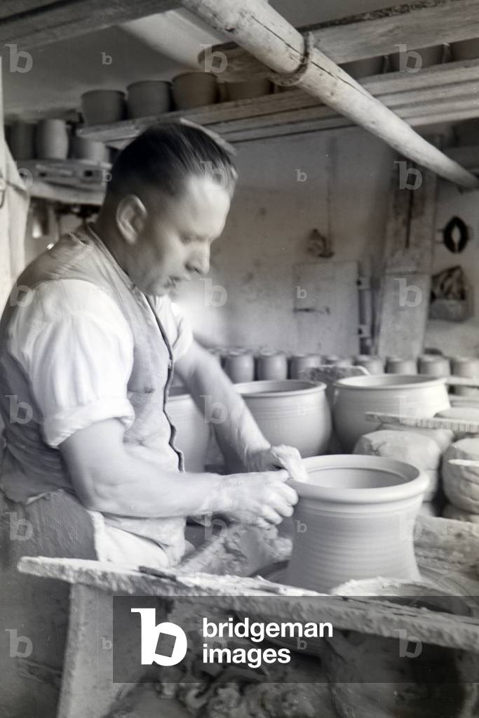 A master potter working on stoneware jars with the pottery wheel in the Kannenbäckerland, Germany 1930s (b/w photo)
