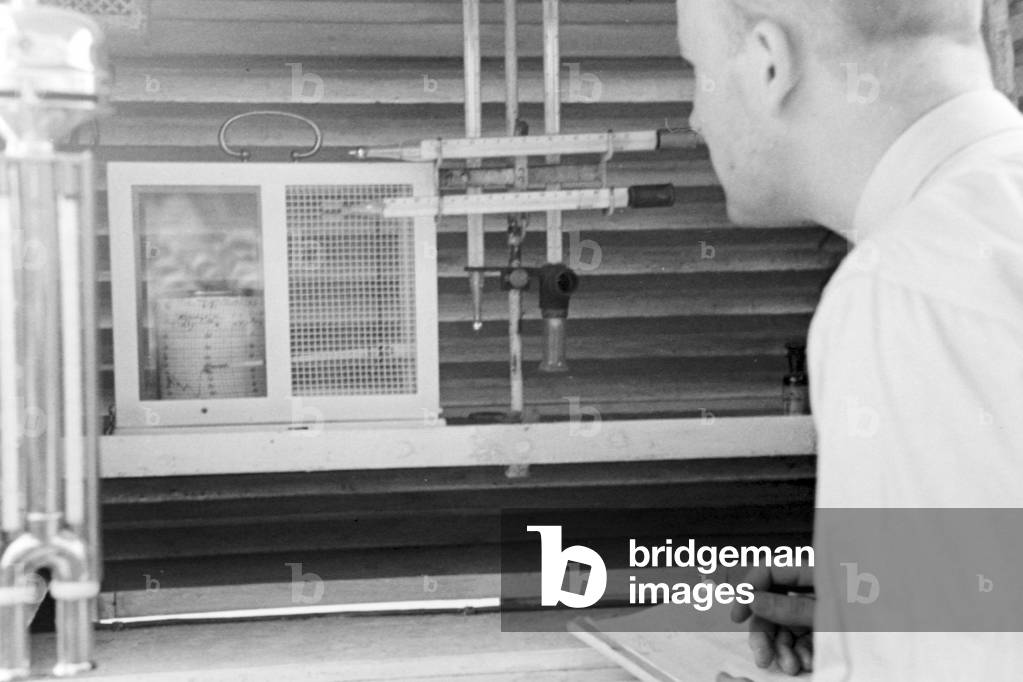 Staff member of a meteorological office measuring the rainfall, Germany 1930s (b/w photo)