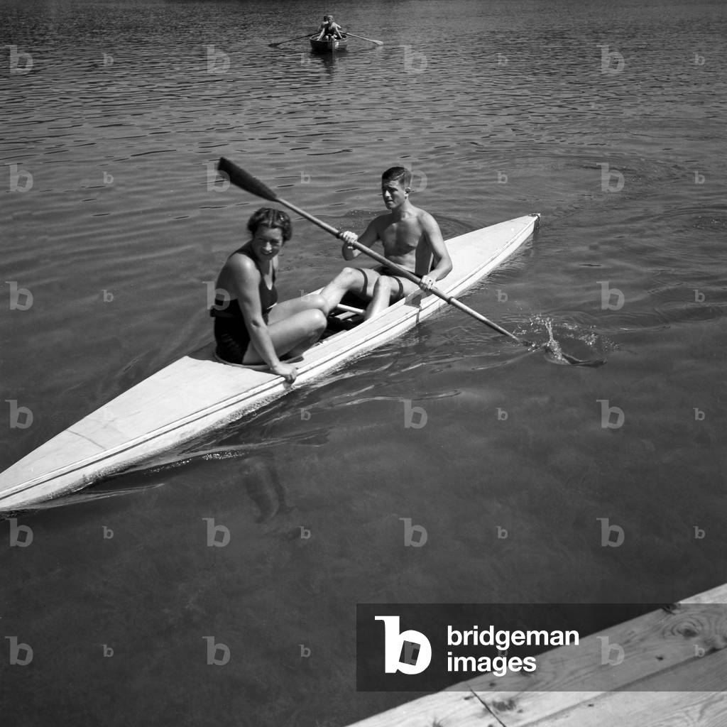 A woman and a man paddling on a lake at Austria, 1930s (b/w photo)