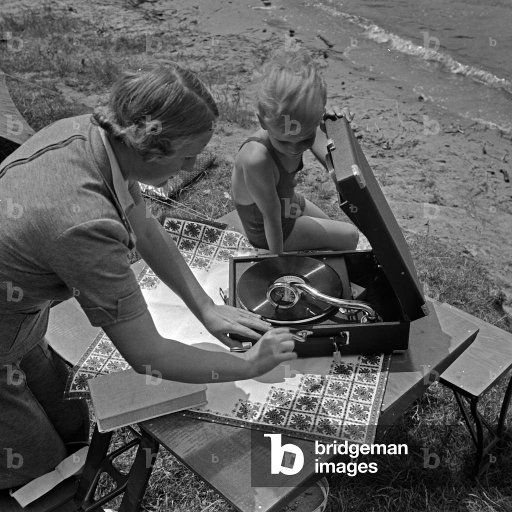A young woman and a little boy putting a record on the record player, Germany 1930s (b/w photo)