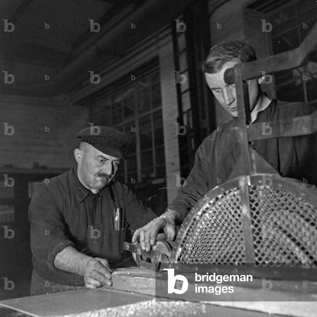 The safety engineer is interviewing a worker at a saw of a roll thread factory, Germany 1930s (b/w photo)