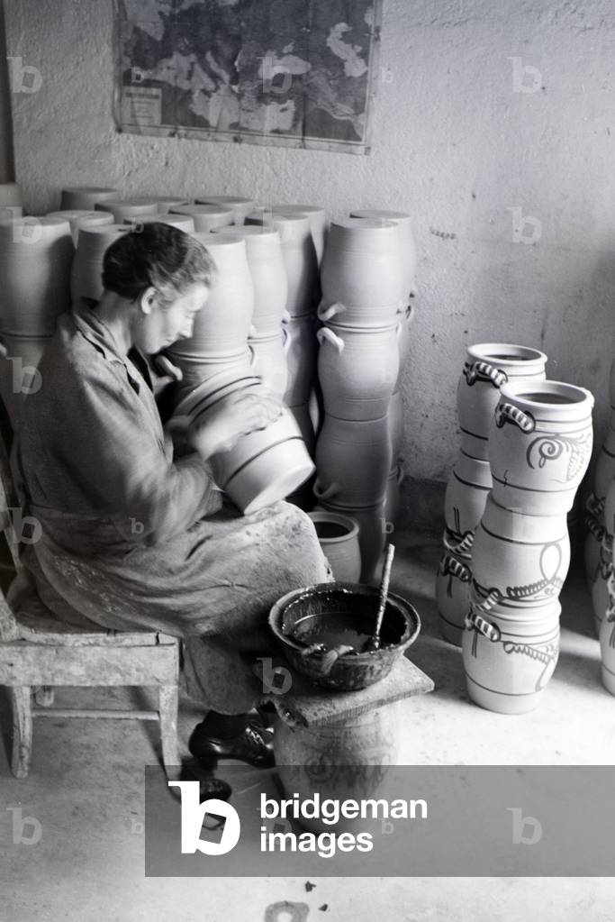 A master potter painting stoneware jars in the characteristic blue colour of the Westerwälder Stoneware, Germany 1930s (b/w photo)