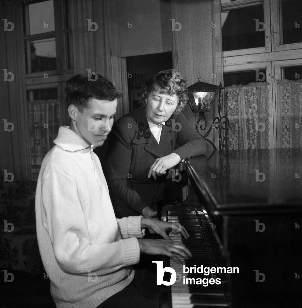 A young man playing a grand piano