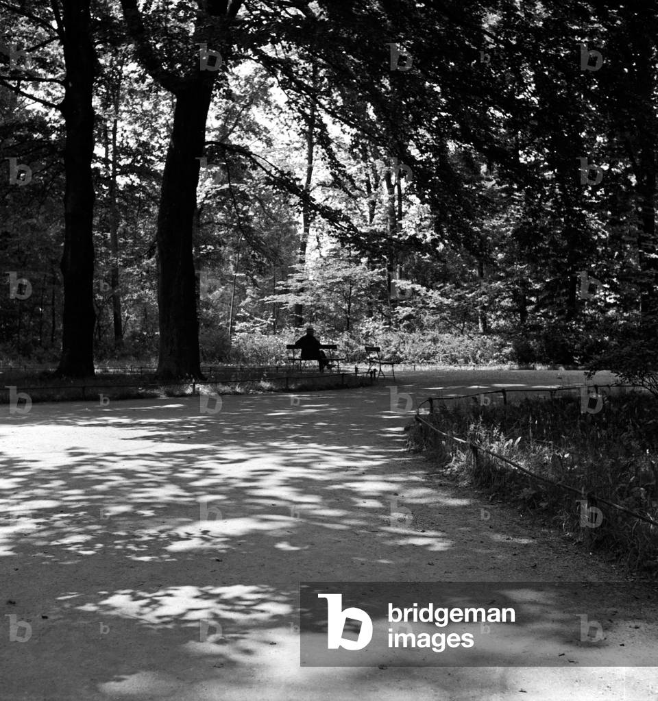 A man sitting on a bench at a public garden in Weimar, Germany 1930s (b/w photo)