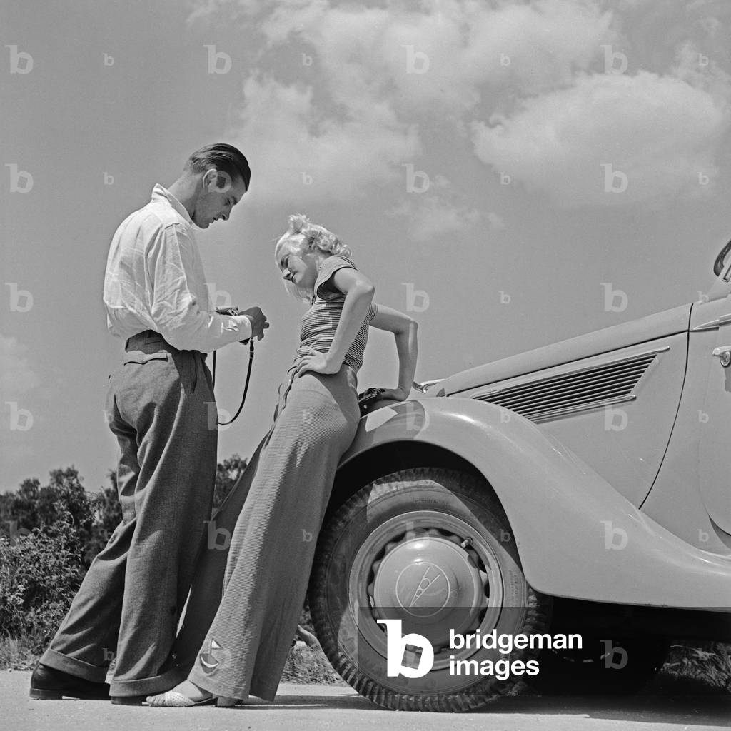 A woman and a man at the bonnet of a Ford V8, Germany 1930s (b/w photo)